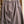 A textured, heathered grayish-purple skirt hanging on a wooden hanger from a rustic wooden ladder.